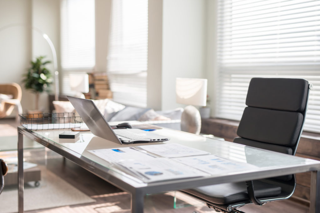 Modern office interior design with office chair and desk in front of windows. Workplace with laptop.