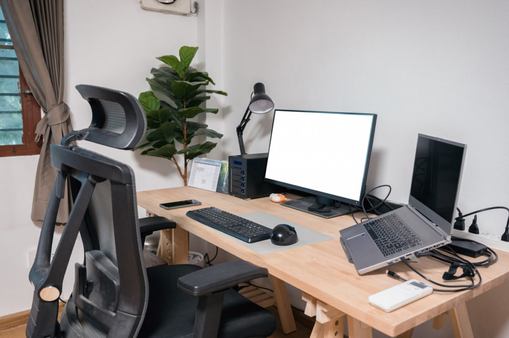 A desk with two computers, a lamp and an ergonomic office chair in an office in El Paso.